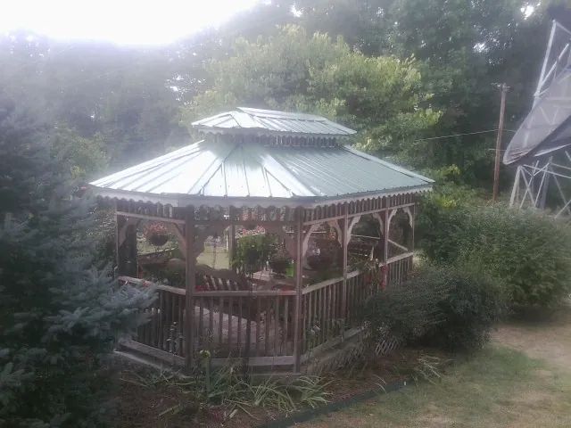 Green metal roof on a backyard gazebo surrounded by garden beds in Malta
