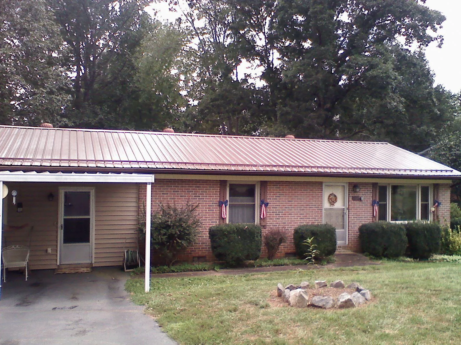 Bronze metal roof and carport on a brick ranch home — Roof Repair work by our crew in Malta